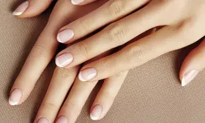 Dłonie z perfekcyjnym manicurem french kombinowany. Delikatny róż i biel podkreślają elegancję.