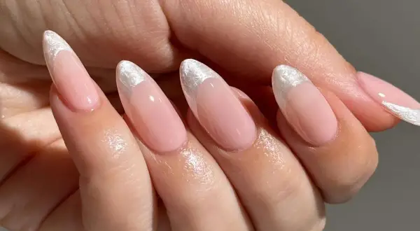 Delikatne, różowe paznokcie w stylu princess nails french z błyszczącym, srebrnym wykończeniem na końcówkach.