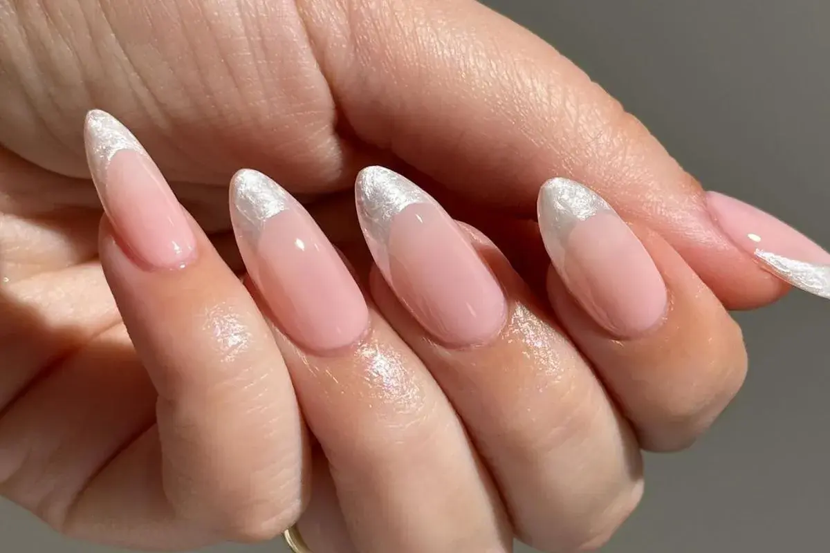 Delikatne, różowe paznokcie w stylu princess nails french z błyszczącym, srebrnym wykończeniem na końcówkach.